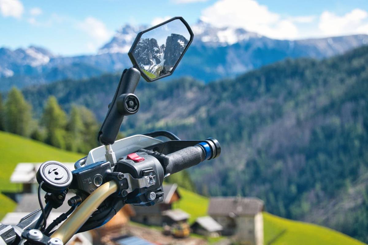 Motorrad-Lenker mit Bergspiegelung im Rückspiegel